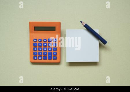 Orange calculator and memo pad, pencil on khaki desk background. top view Stock Photo