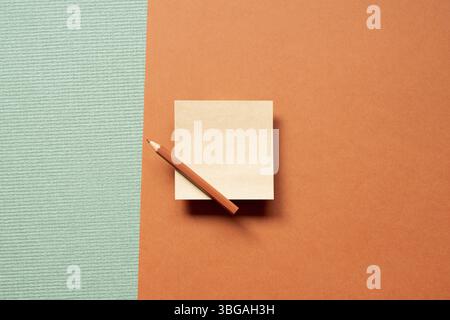 Blank memo pad brown kraft paper with colored pencil isolated on green and red background. top view, copy space Stock Photo
