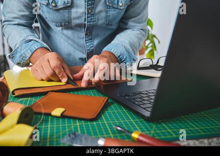Leather craftsman working with leather in his workshop, cutting, marking and preparing leather goods Stock Photo