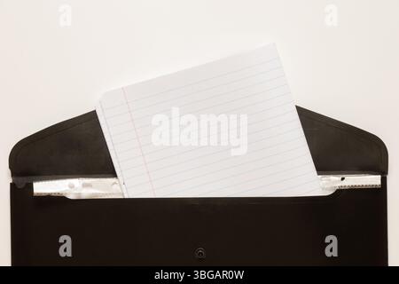 Black business folder with inserted school notebook in a line on a white background as a concept of work, documents and education Stock Photo
