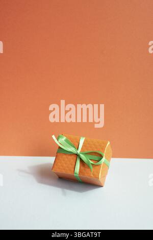 Orange gift box on gray desk. red wall background Stock Photo