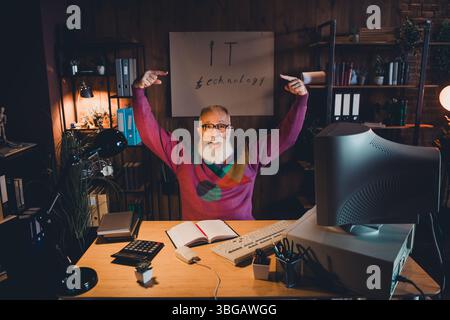 Elderly man working at desk in cozy home office, focused on technology and programming Stock Photo