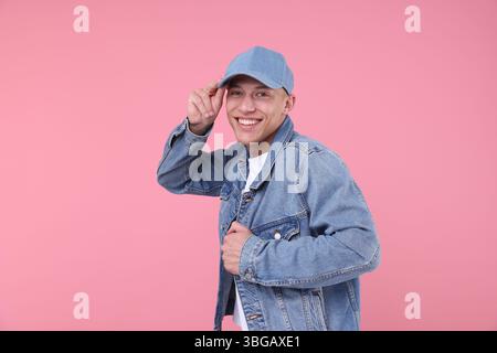 Young man wearing stylish denim baseball hat on pink background Stock Photo