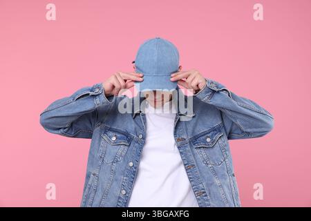 Young man wearing stylish denim baseball hat on pink background Stock Photo