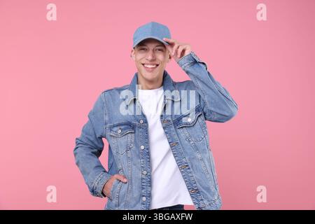 Young man wearing stylish denim baseball hat on pink background Stock Photo