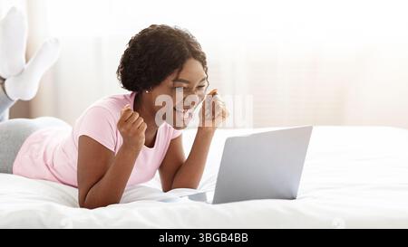Emotional black woman looking at laptop screen and screaming Stock Photo