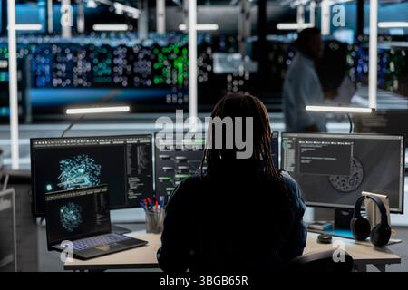 Data center software developer uses AI visualization tool to oversee automated repetitive tasks. Server room worker adapting infrastructure systems based on data analytics graphs using PC Stock Photo