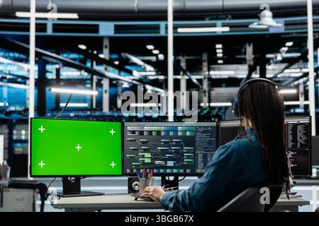 Programmer in data center using isolated screen computer to check equipment performance upgrading infrastructure. IT expert doing maintenance on supercomputers in servers room using chroma key PC Stock Photo