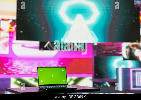 Laptop running isolated mockup screen surrounded by funky visual art clips, glowing in the dark and creating a clubbing atmosphere. Nightlife ambiance with modern beats and lights. Stock Photo