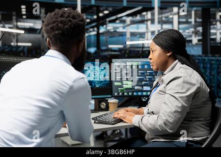 Data center engineering team using artificial intelligence neural networks technology. Professional and coworker in server room using AI programming language to configure specialized hardware Stock Photo