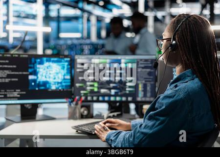 Data center support expert talking in headset microphone, supporting engineering team doing equipment maintenance. Employee in server farm coordinating technicians using mic Stock Photo