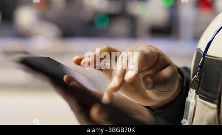 Close up of engineer in industry 4.0 plant designing robotic production lines using CAD application on tablet. Smart factory specialist uses software to optimize floor layouts, camera B Stock Photo