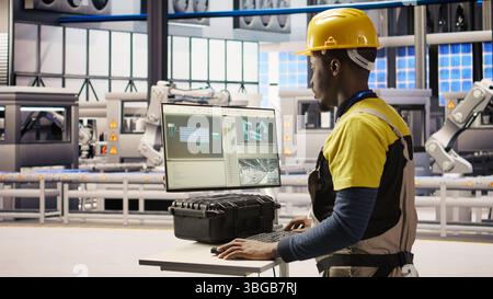 Engineer overseeing solar panel production lines equipment using PC software. Worker maintaining photovoltaic assembly systems in automated industry 4.0 factory using computer, camera A Stock Photo