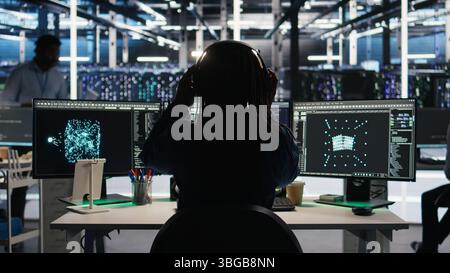 Data center engineer implements AI virtualization frameworks to optimize server clusters. Server hub IT professional doing artificial intelligence predictive analysis, camera A Stock Photo