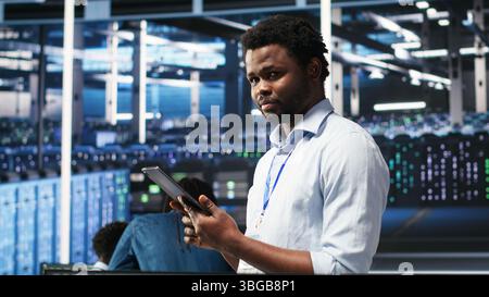 Data center technician uses node tree programming interface to identify equipment performance issues. Engineer reviews data analysis graph in server hub to minimize hardware failures, camera B Stock Photo