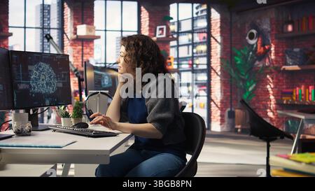 Teleworking developer using computer for artificial intelligence brain computing through self learning algorithms. Agency IT engineer works with AI deep neural networks on desktop PC. Camera A. Stock Photo