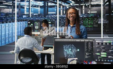 Portrait of upbeat server hub software developer using node tree software to optimize system health. Radiant data center staff member analyzing rigs issues using AI visualization, camera A Stock Photo