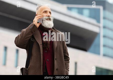 Wealthy senior man having conversation on phone outdoors Stock Photo