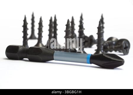 Black screws and drill bits arranged creatively on white background Stock Photo