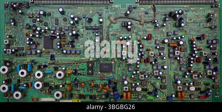 Close-up of a green circuit board, highlighting various electronic components, soldering points, and intricate wiring Stock Photo