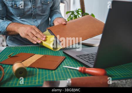 Craftsman working leather in his workshop preparing materials for creating new products Stock Photo
