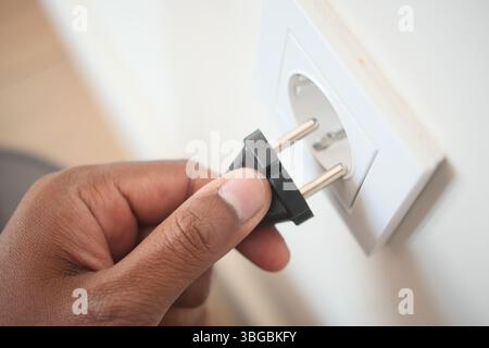 Hand inserting plug into electrical outlet in a home Stock Photo