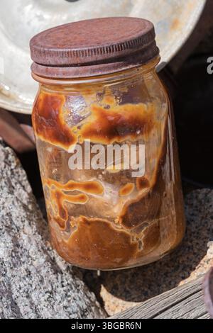 ancient discolored peanut butter in old glass jar with rusting lid in abandoned mining camp in the Inyo Mountains of California Stock Photo