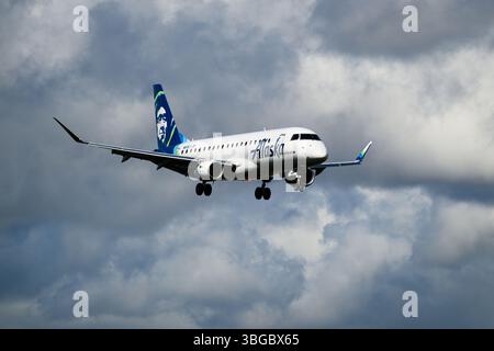 Everett, WA, USA - May 19, 2025; Alaska Airlines Embraer 175 landing with storm clouds registration N645QX Stock Photo