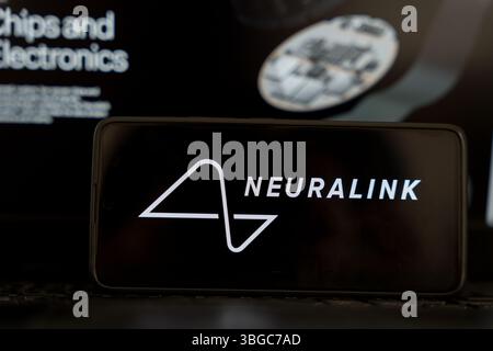 Smartphone screen showing Neuralink logo with background related to brain chip technology and electronics. June 5, 2025 Stock Photo