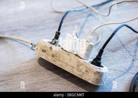 A variety of wires are connected into a power strip, providing multiple electrical outlets for various devices to utilize electrical power Stock Photo