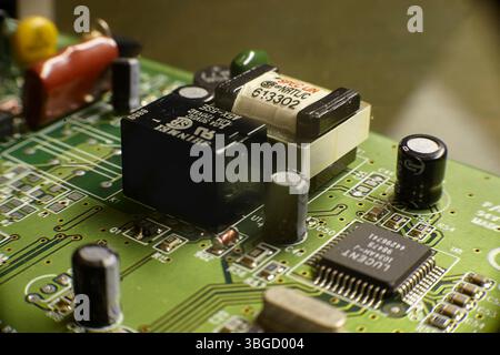 Close-up of a printed circuit board featuring various electronic components, including a siemens relay, capacitors, resistors, and an integrated circu Stock Photo
