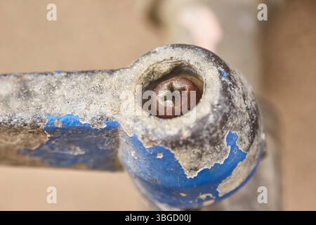 Close-up of rusty screw securing lever of old, weathered, and worn-out valve, showing signs of age and decay Stock Photo
