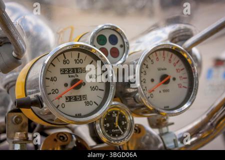 Close-up of a vintage motorcycle dashboard displaying various gauges, including speedometer, odometer, clock, and rpm gauge Stock Photo