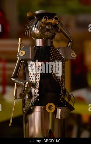 Recycled metal art sculpture holding binoculars, made from a wine bottle, showcasing creativity and sustainability Stock Photo