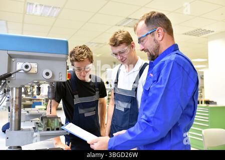 trainer and apprentice in technical vocational training at a drilling machine Stock Photo