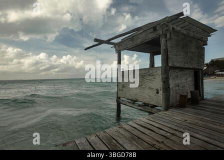 Isla Mujeres, Mexico 1 January 2025: An old wooden lifeguard tower stands on a pier overlooking the caribbean sea in isla mujeres, mexico, with cloudy Stock Photo