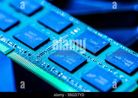 Milan, Italy 1 January 2025: Ram modules on a circuit board, illuminated with blue light, represent computer memory and processing power Stock Photo