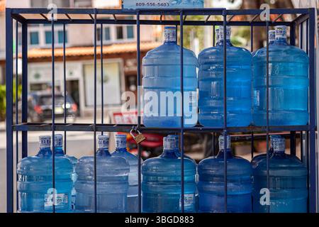 Bayahibe, Dominican Republic 1 January 2025: Big plastic water bottles stacked and locked in a metal rack in dominicus, dominican republic Stock Photo