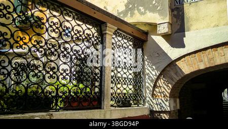 Venice, Italy 1 January 2025: Sunlight illuminating a decorative metal gate, casting intricate shadows on an old wall in venice, italy Stock Photo