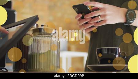 Image of falling yellow dots over people using payment terminal Stock Photo