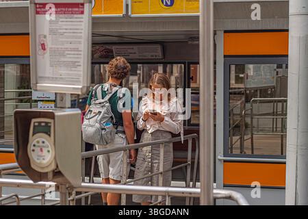 Venice, Italy 1 January 2025: Young woman using smartphone while waiting at vaporetto stop with her friend in venice, italy Stock Photo