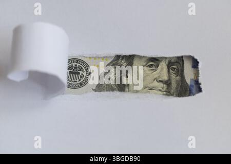 Benjamin Franklin macro peeking through torn white paper Stock Photo