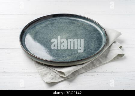 An empty grey textured plate with a napkin on a white wooden table Stock Photo