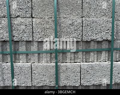 Stack of gray aerated concrete blocks tightly packed and secured with green straps. No people. Useful for construction industry and background use. Stock Photo