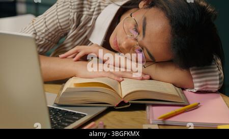 Sleeping tired woman exhausted American Latina ethnic girl weary lazy female high school student overworked businesswoman relax nap on table boring Stock Photo