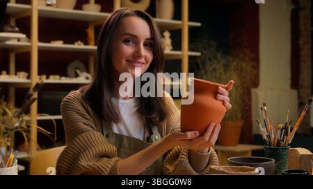 Caucasian woman artist painter decorator art designer potter handmade workshop female small business owner girl painting pot clay modeling handcraft Stock Photo