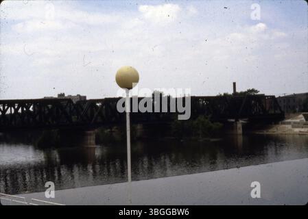The image shows a street light next to the W Main Street bridge, looking southeast over the Scioto River, with a view of a railroad bridge and Sunshine Terrace Apartments in the distance. Stock Photo