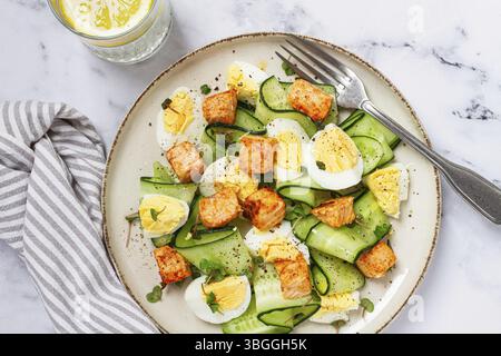 Delicious salmon and egg salad served on a plate with fresh cucumber and herbs for a healthy meal at lunchtime Stock Photo