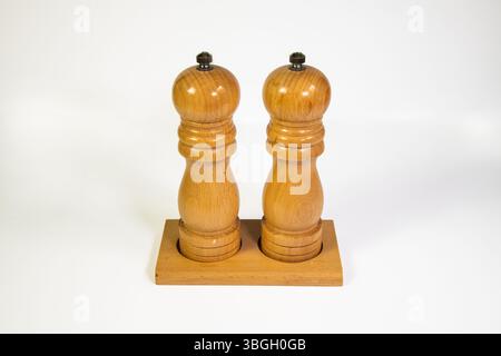 Wooden salt and pepper mills isolated on a clean white background, minimalist kitchenware concept. Stock Photo