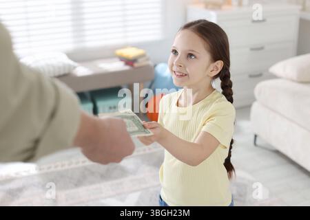 Father giving his daughter pocket money at home, closeup Stock Photo